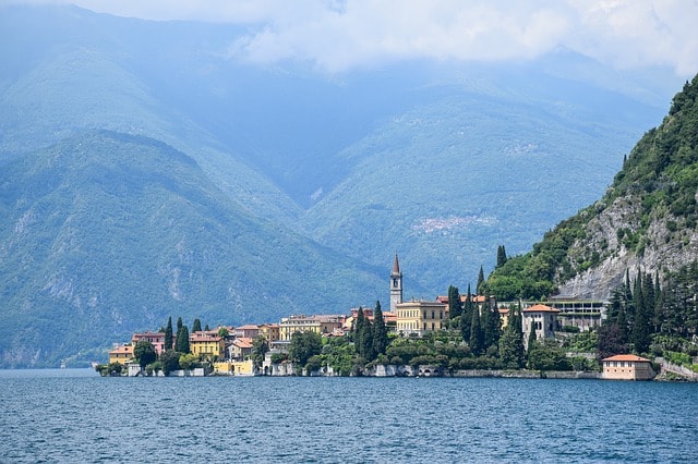 Le lac de Côme entourée de montagnes. Au milieu, un joli petit village avec son église. 