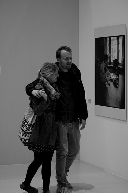 Photo en noir et blanc d'un couple admirant des tableaux d'artiste dans un musée à Singapour.