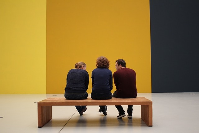 Trois personnes assises sur un banc discutent dans le musée moderne de Tel-Aviv.