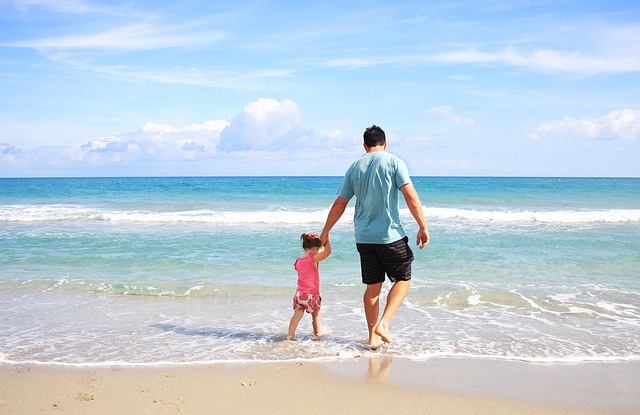 Un père et sa petite fille jouent sur la plage.