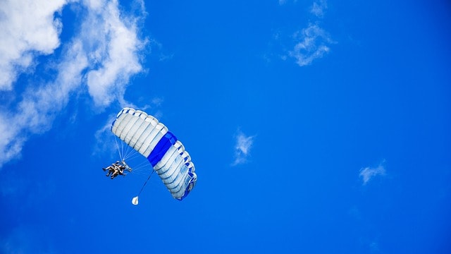 Deux personnes effectuant un saut en parachute en tandem sous le ciel bleu de Rome.
