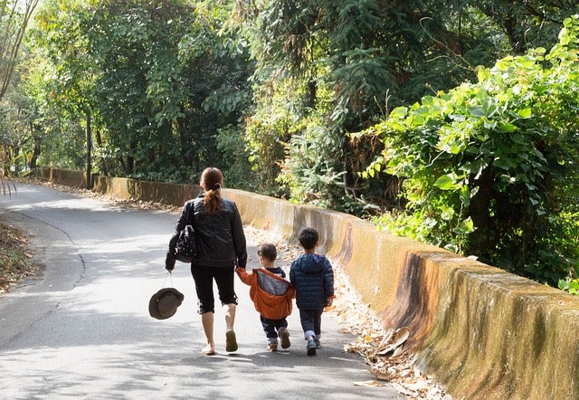 Maman et deux enfants marchant dans un parc.