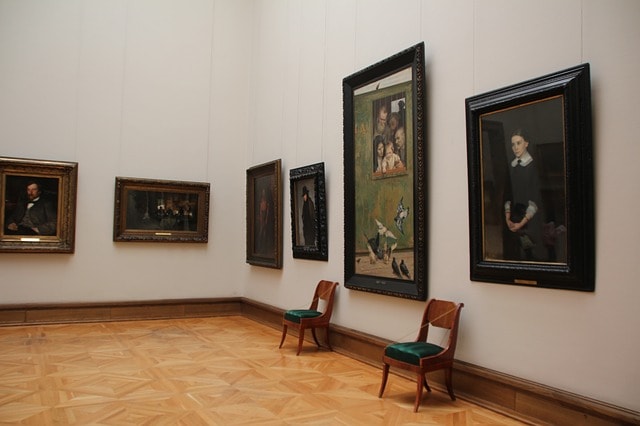 Quelques tableaux accrochés sur un mur blanc dans une salle de musée.