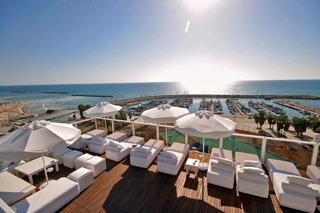 Vue sur la Marina et ses bateaux depuis la terrasse avec transats et parasols d'un hôtel à Tel-Aviv.