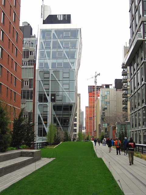 Promeneurs sur la Highline se faufilant entre les buildings de New York.