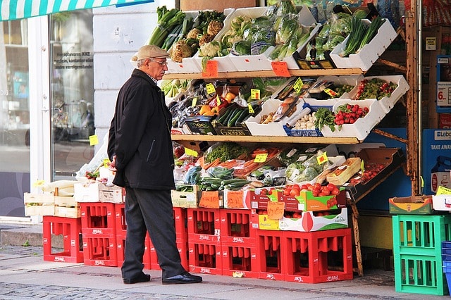 Échoppe de fruits et légumes frais dans un marché couvert de Copenhague et le vendeur.