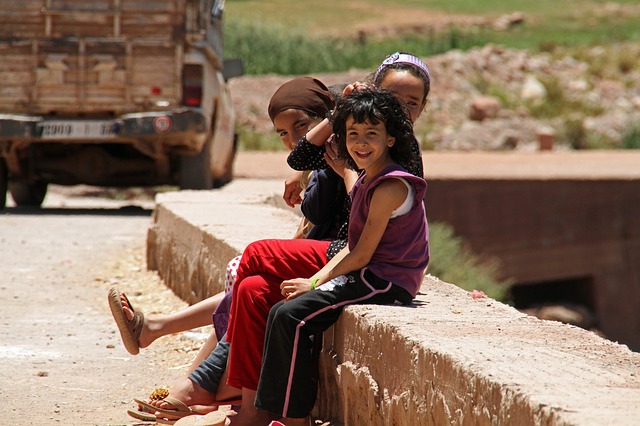 Trois enfants souriants dans une rue vers Marrakech.