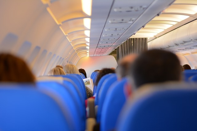 Vue de dos des passagers installés dans leur siège à l'intérieur d'un avion en direction de Cancun.