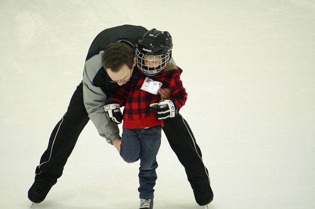 Papa donnant des leçons de patinage à son fils à Montréal.