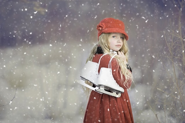 Jolie petite fille en rouge apportant ses patins sous la neige.