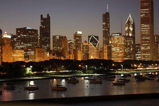 Gratte-ciel de Chicago et ses lumières se reflétant dans la rivière où sont amarrés quelques bateaux.