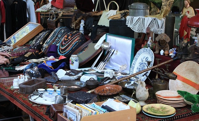 Étal de brocante avec des livres, pièces en céramique, bijoux anciens, etc.