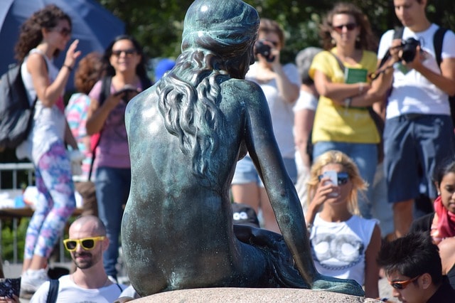 La petite sirène vue de dos photographiée par des touristes à Copenhague.