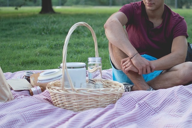 Jeune homme regardant un panier pique-nique dans un parc.