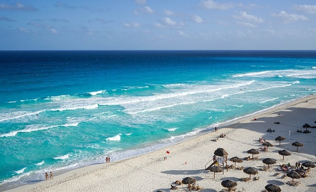 Magnificent sandy beach equipped with umbrellas and turquoise sea under a blue sky in Cancun.