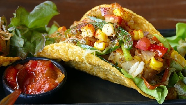 Un délicieux taco généreux garni de maïs, de poivrons, tomates et oignons et accompagné d'une sauce tomate.