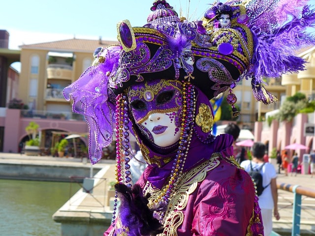 Vénitien arborant un costume traditionnel violet avec masque.