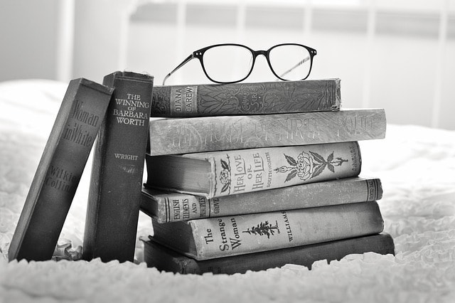 Pile de livres avec lunettes en noir et blanc.
