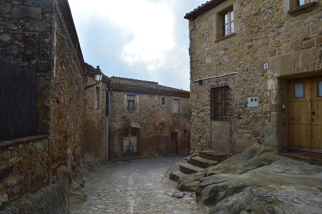 Village médiéval en pierres traversé par une ruelle.