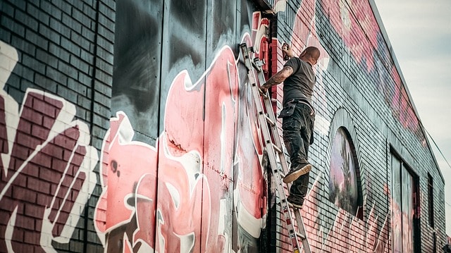 Homme entrain de dessiner sur un mur.