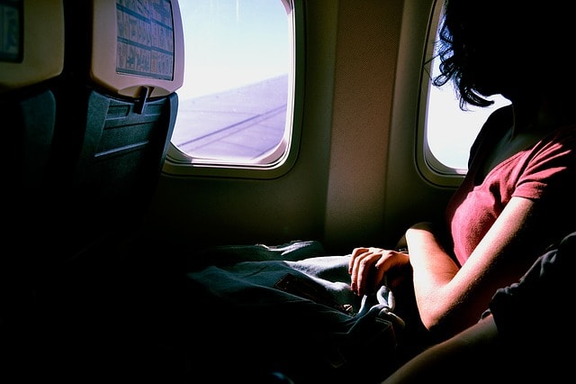 Une personne installée confortablement en avion avec une couverture.