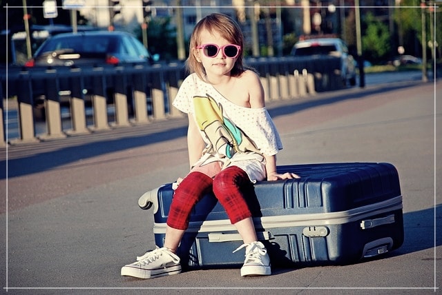 Une petite fille sur sa valise prête à embarquer dans l'avion.