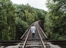 Un homme marchant seul sur les rails d'un train.