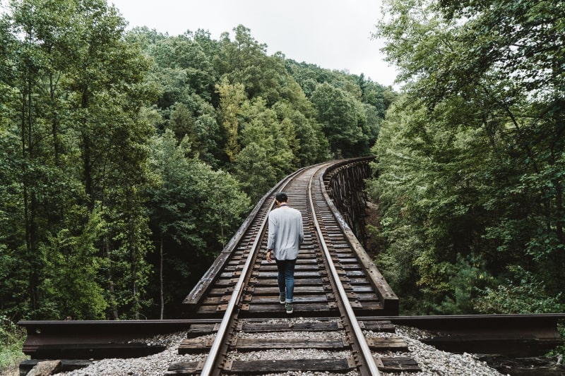 Un homme marchant seul sur les rails d'un train.