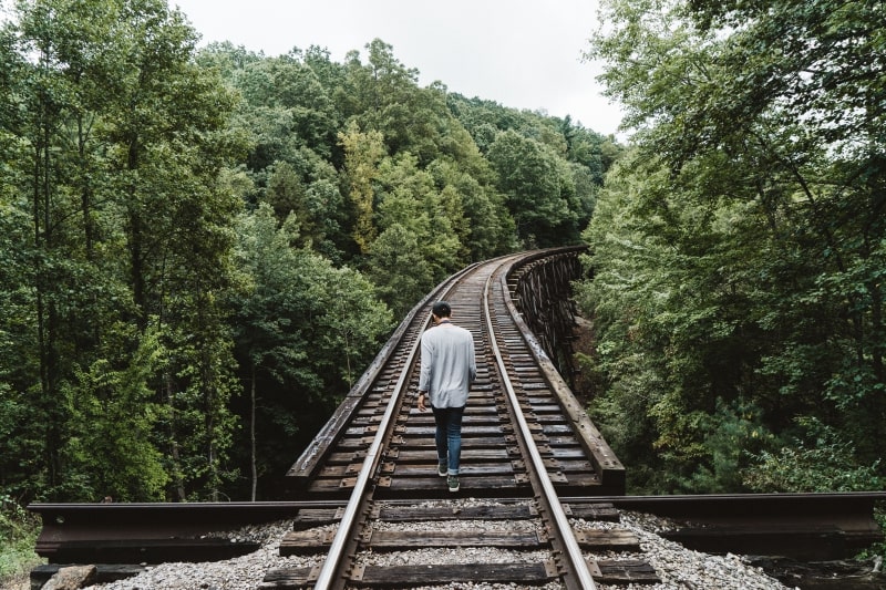 Un homme marchant seul sur les rails d'un train. 