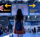 Une femme à l'aéroport se tenant devant deux panneaux indiquant des directions différentes pour le Brexit et l'Union Européenne.