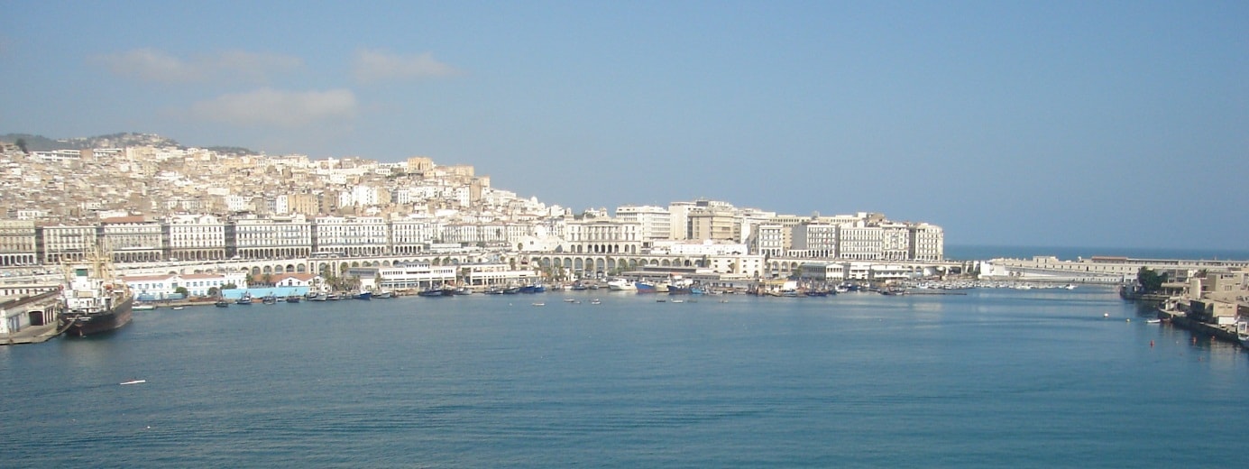 Un vol Alger pas cher avec Algofly illustré par la ville blanche en bord de mer sous un ciel bleu.