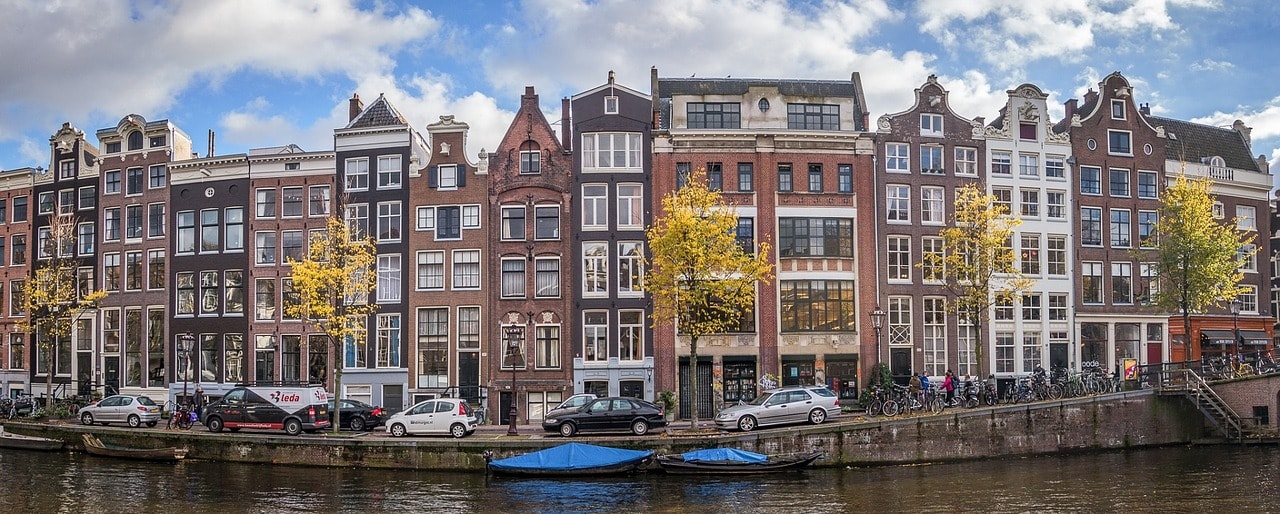 Un vol Amsterdam pas cher avec Algofly illustré par des immeubles de couleur au bord du canal.