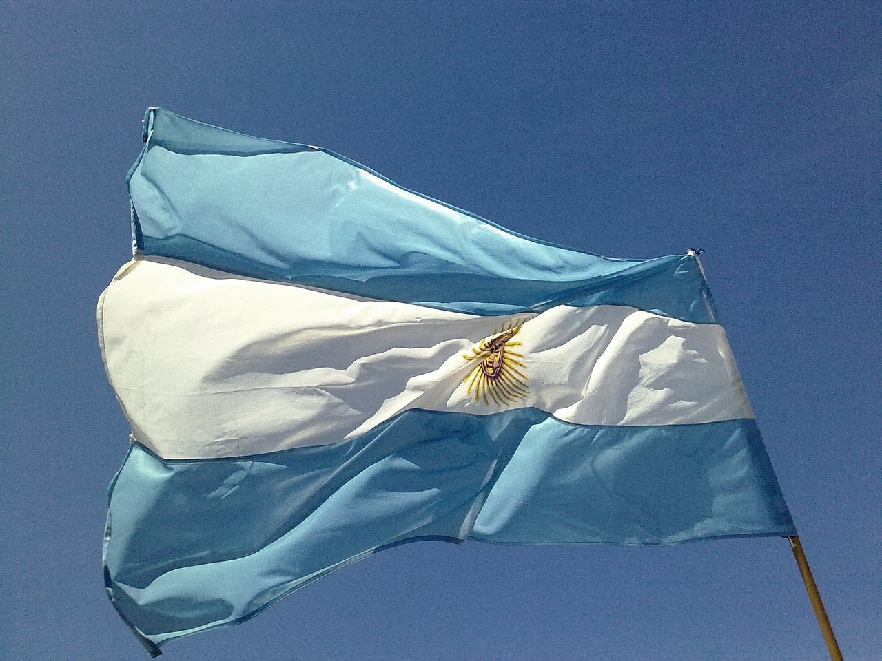 Un vol Argentine pas cher avec Algofly illustré par un drapeau national bleu, blanc et son soleil jaune en plein centre.