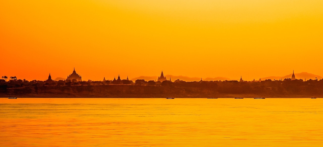 Un vol Birmanie pas cher avec Algofly illustré par un paysage orangé avec des temples donnant sur la rive.