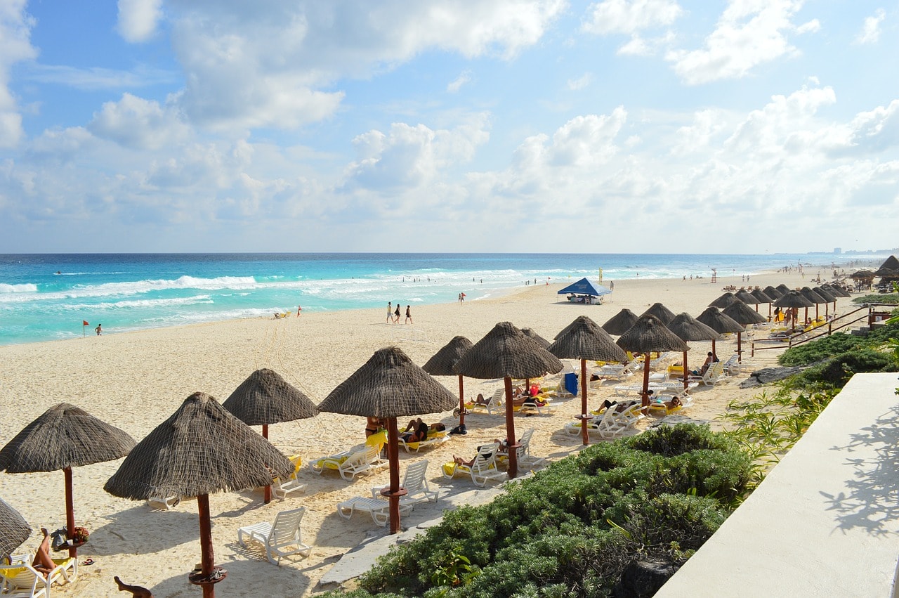 Un vol Cancún pas cher avec Algofly illustré par une plage de sable blanc sur une mer turquoise.