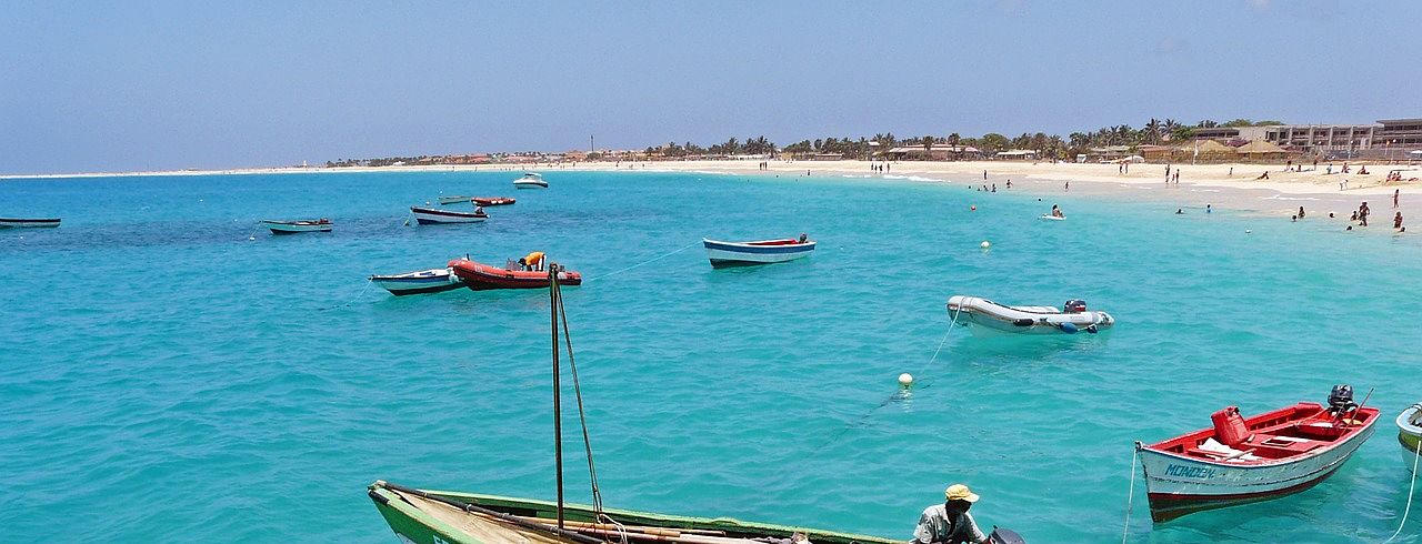 Un vol Cap Vert pas cher avec Algofly illustré par une mer turquoise et de petits bateaux amarrés.