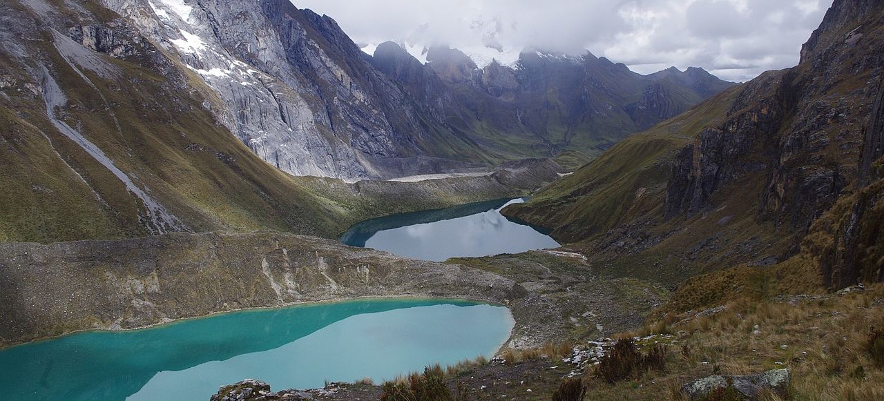 Un vol Chili pas cher avec Algofly illustré par des lacs d'eau turquoise entre les montagnes sous un ciel nuageux.