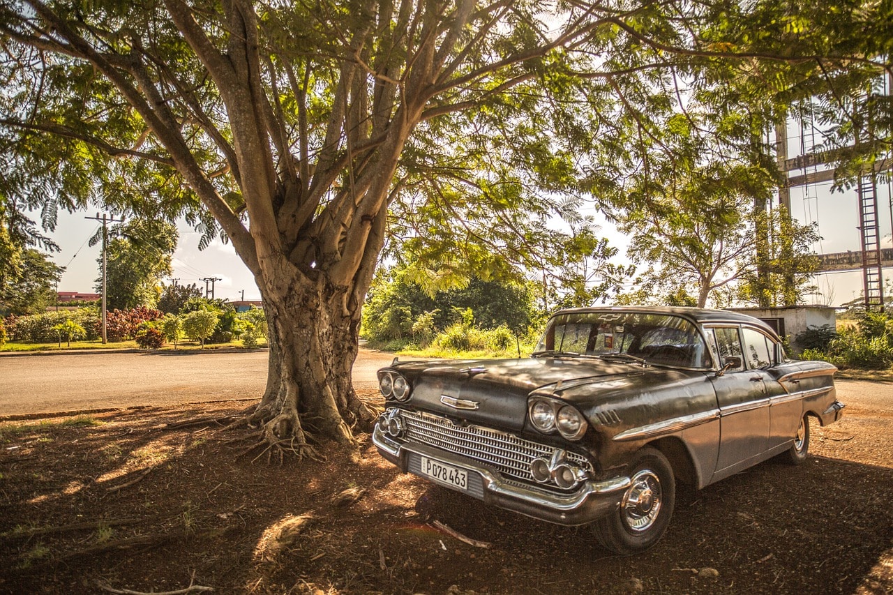 Un vol Cuba pas cher avec Algofly illustré par une voiture ancienne des années 70 garée sous un arbre.