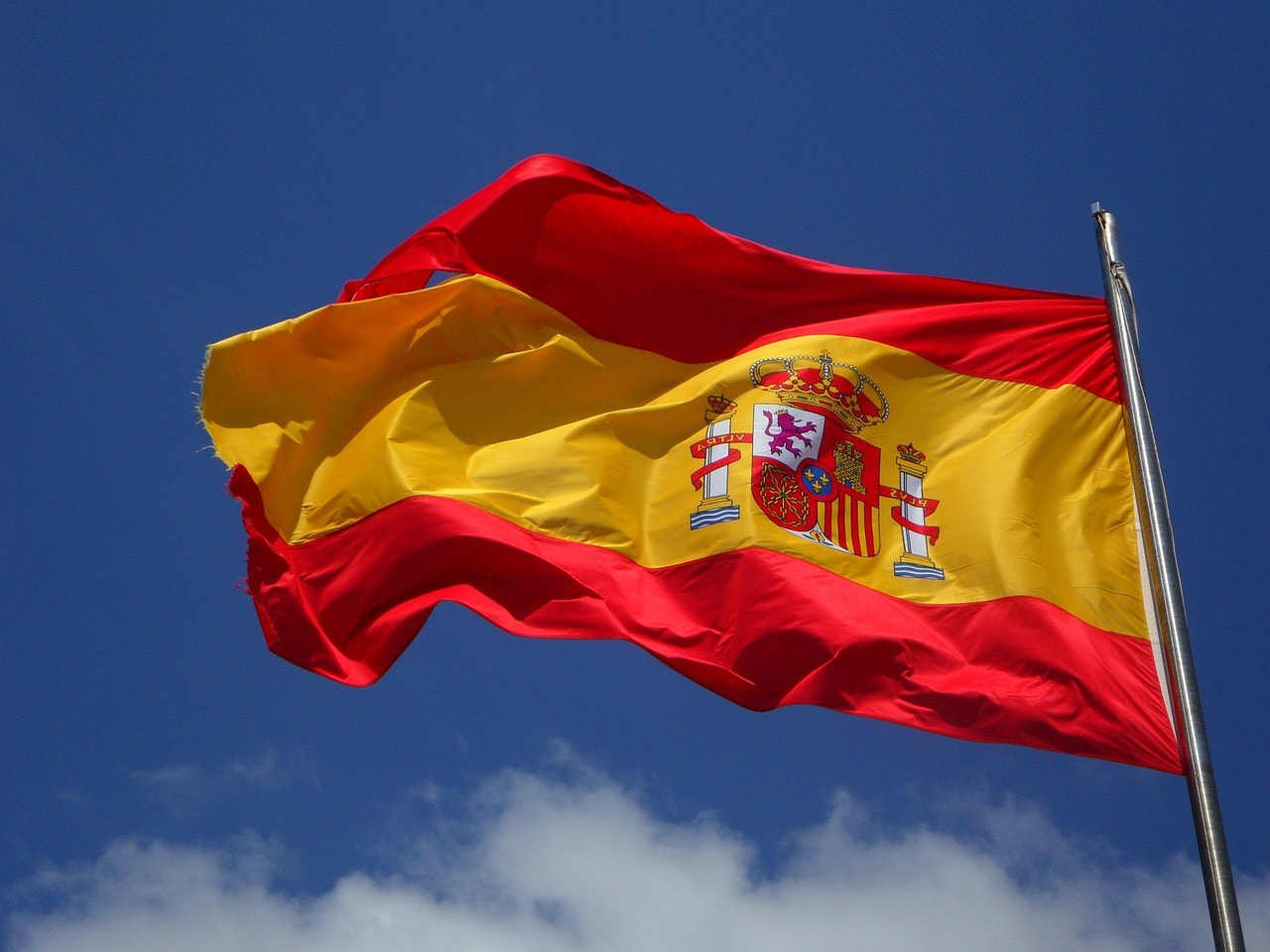 Un vol Espagne pas cher avec Algofly illustré par son drapeau national jaune et rouge accompagné de son blason.