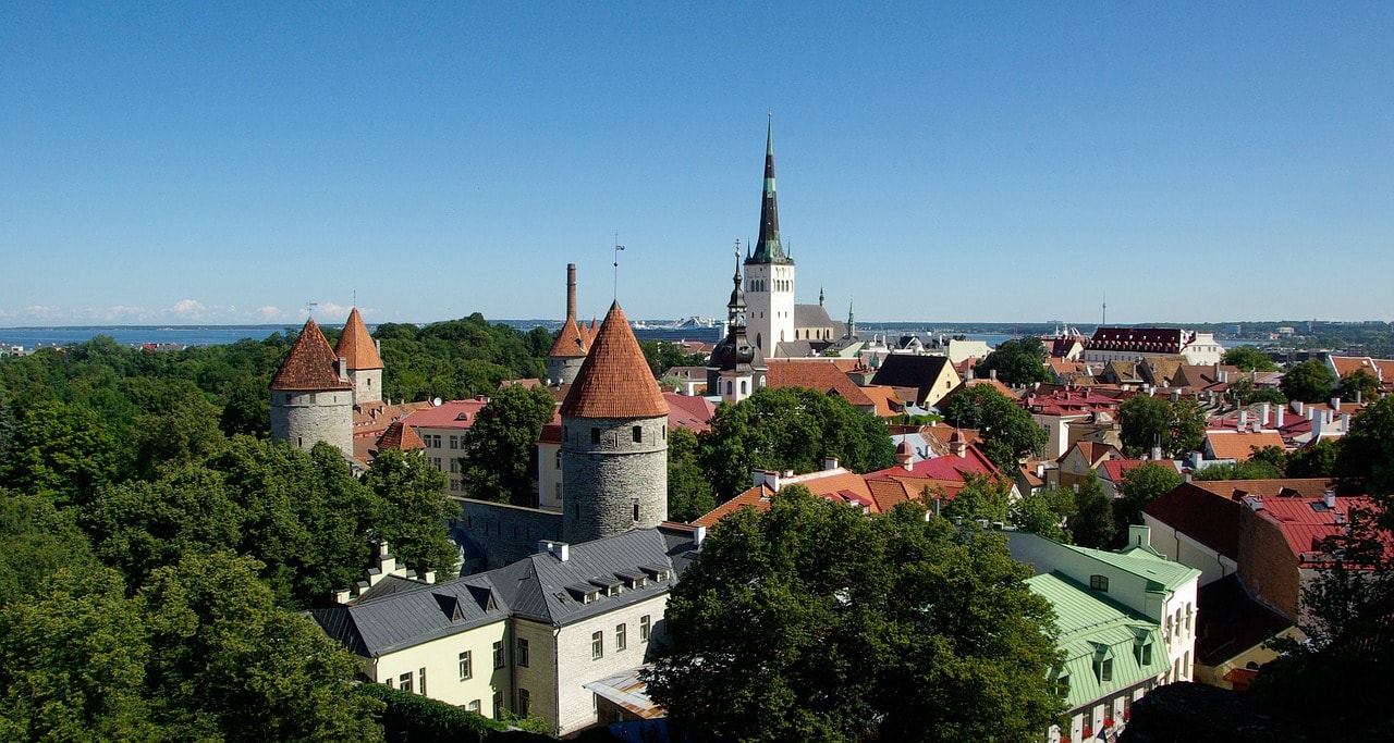 Un vol Estonie pas cher avec Algofly illustré par le château de la ville fortifiée et l'église Saint-Olaf de Tallinn.