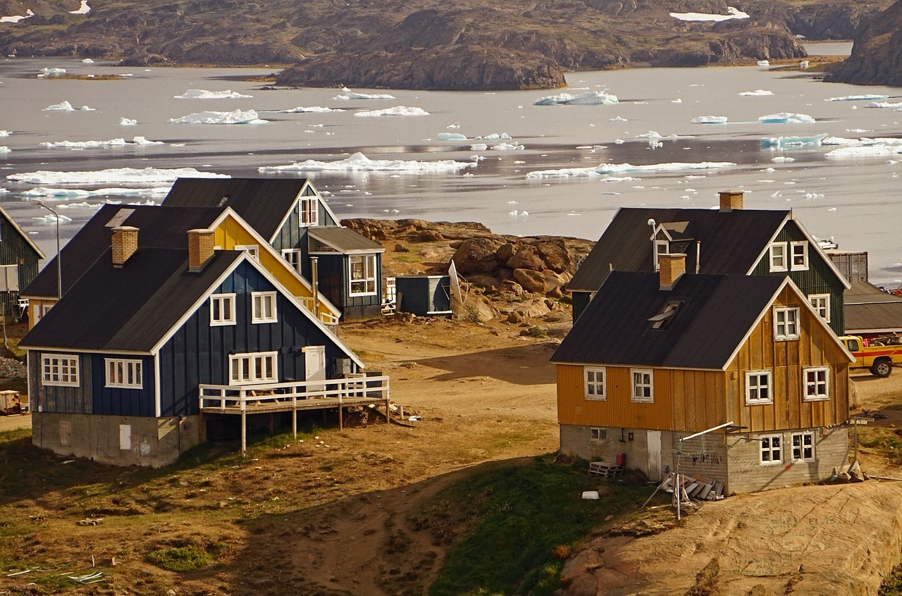 Un vol Groenland pas cher avec Algofly illustré par des maisons typique de Tasiilaq dans un univers d'eau, de roche et de glace.