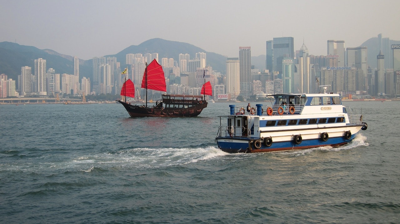 Un vol Hong Kong pas cher avec Algofly illustré par la baie Victoria sur laquelle naviguent bateaux anciens et récents.