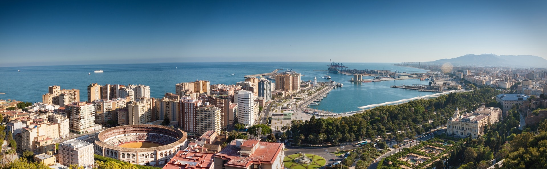 Un vol Malaga pas cher avec Algofly illustré par l'arène de plaza de toros et le port non loin.