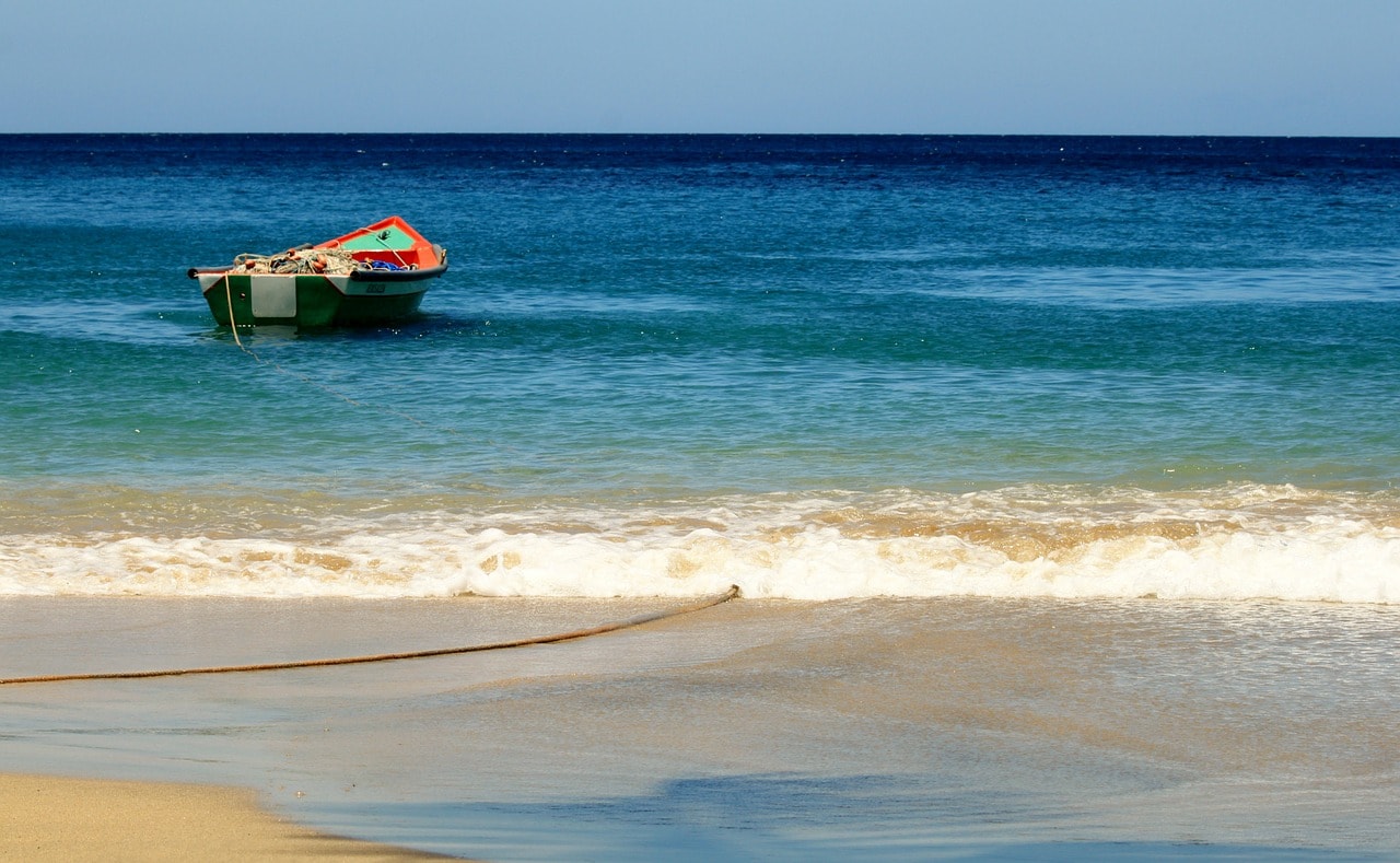 Un vol Martinique pas cher avec Algofly illustré par une petite barge sur une mer bleue intense.