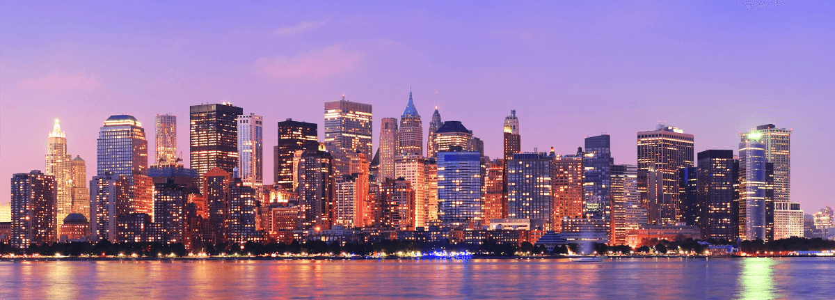 Un vol New York pas cher avec Algofly illustré par Manhattan éclairé de nuit dans une atmosphère violette.