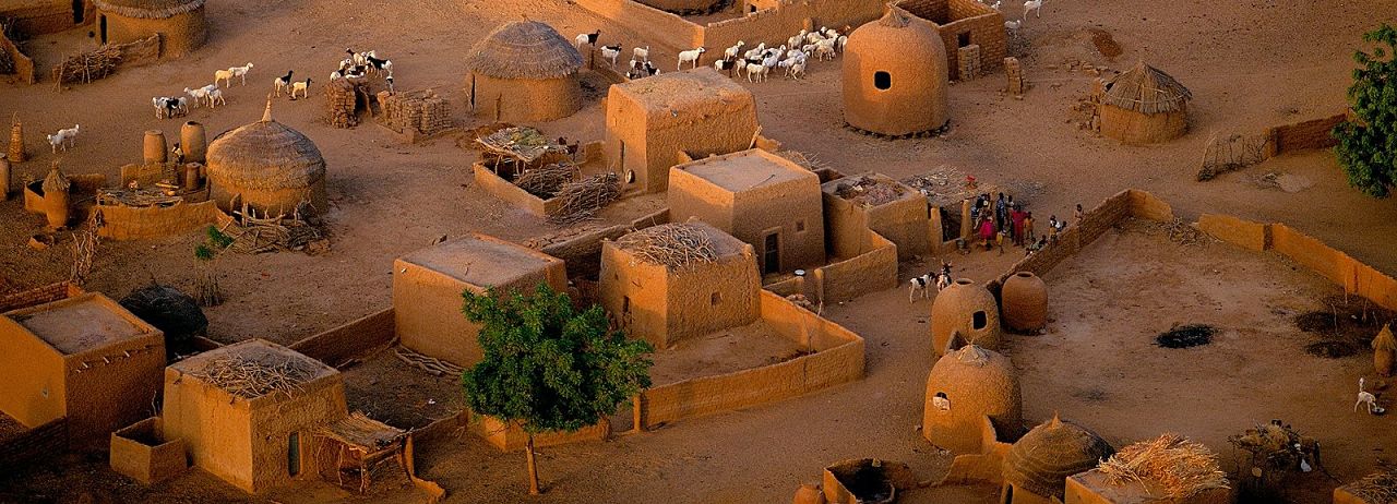 Un vol Niger pas cher avec Algofly illustré par un village typique fait de maisons en terre orange.