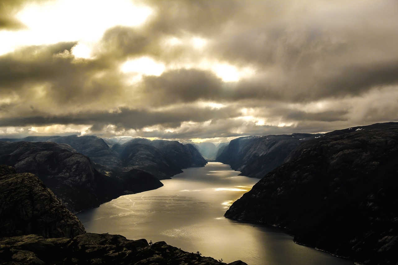 Un vol Norvège pas cher avec Algofly illustré par un Fjord sous un ciel ombragé.