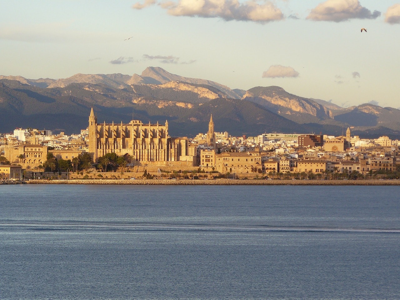 Un vol Palma de Majorque pas cher avec Algofly illustré par la cathédrale de la vielle ville devant un plan d'eau.