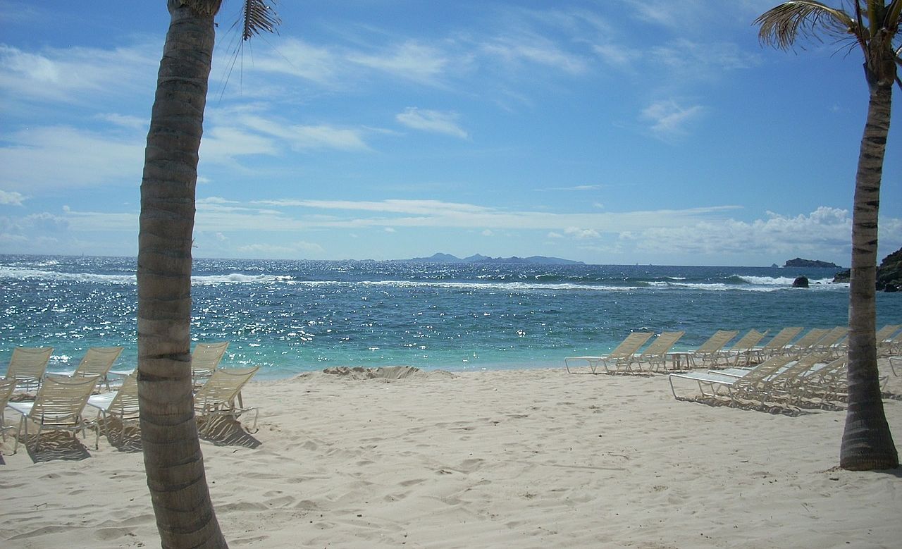 Un vol Saint Martin pas cher avec Algofly illustré par un avion de ligne rasant la plage pour atterrir non loin.