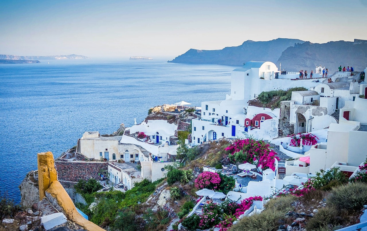 Un vol Santorin pas cher avec Algofly illustré par un village blancs à coupoles bleues dressé devant la mer Egée.